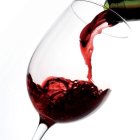 Pouring Red Wine into Tilted Glass on White Background