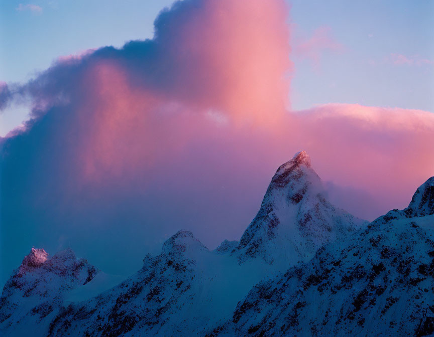 Majestic snow-covered mountain peaks at sunset with dramatic clouds