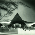 Futuristic complex with pyramid-like structures under starry sky and moon, lit pathways, small figures