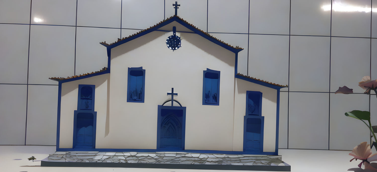 Traditional white church model with blue doors and windows on tiled background with flower.