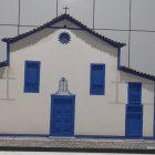 Traditional white church model with blue doors and windows on tiled background with flower.