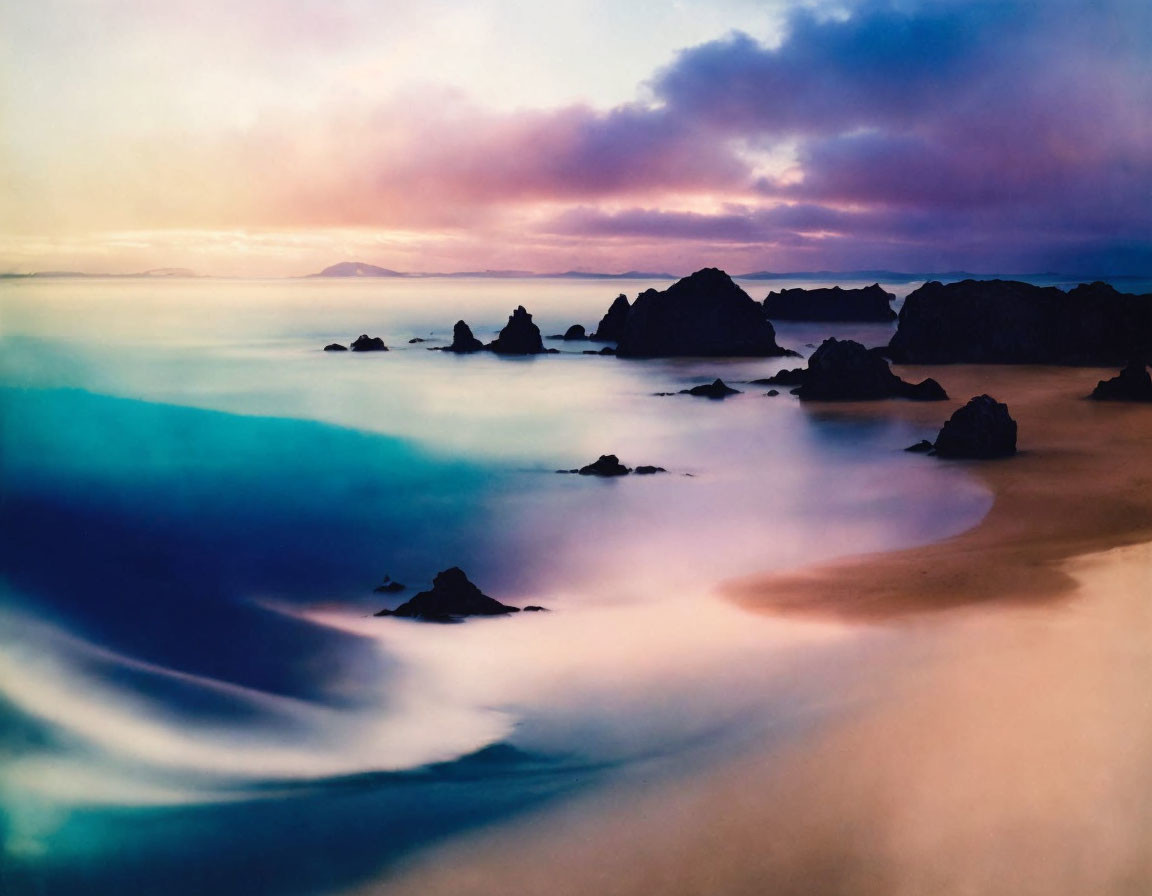 Twilight beach scene with smooth waters and rocky outcrops