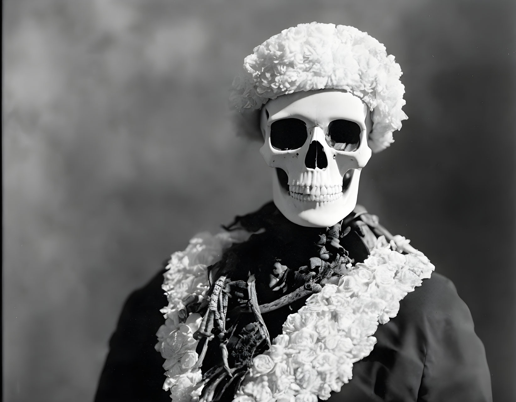 Monochrome photo: person in skeleton makeup with floral headpiece & dark outfit.