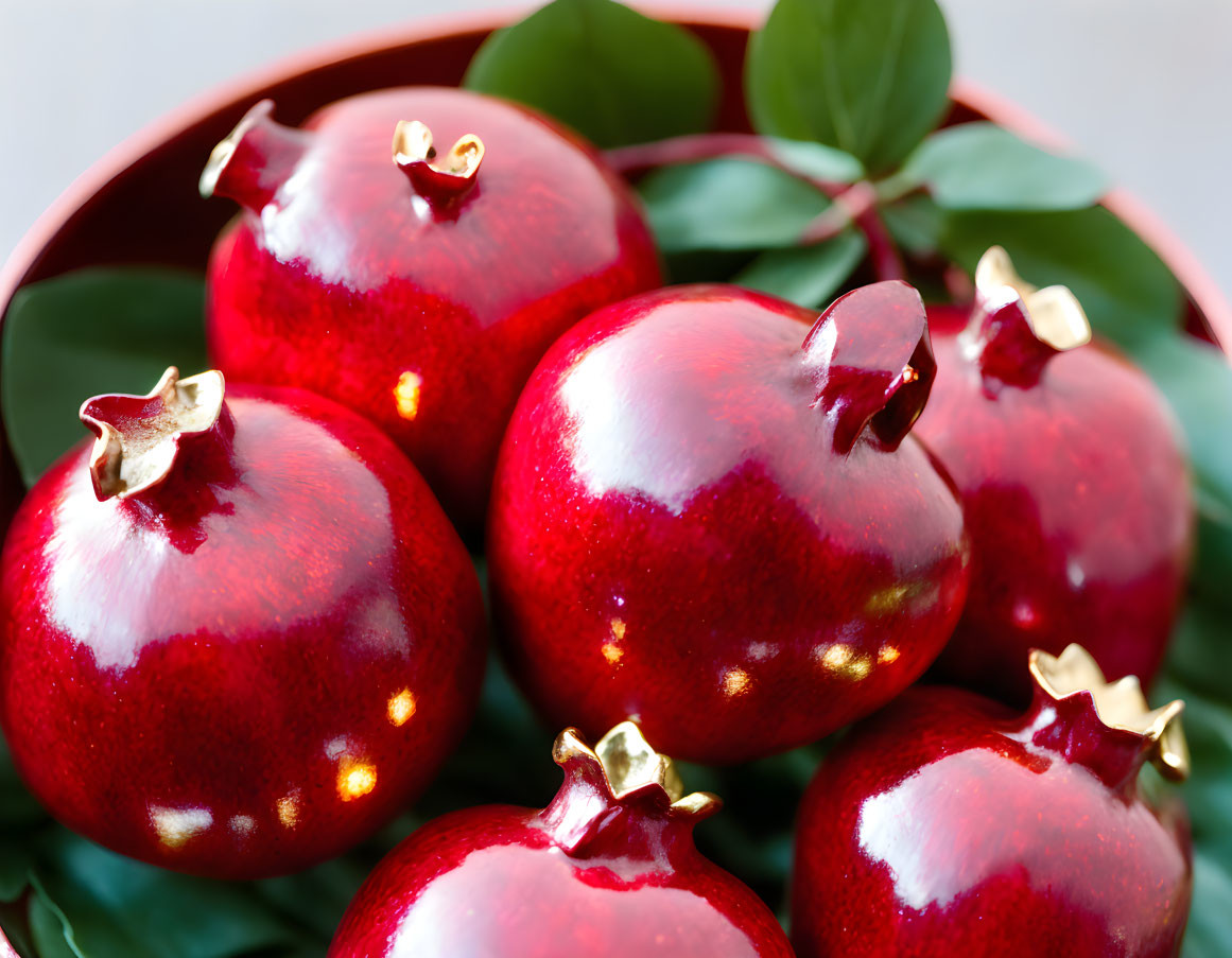 Vibrant red pomegranates with green leaves on white background