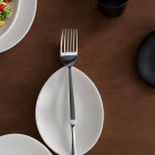 Metal fork on white plate in modern table setting with dishes and cup