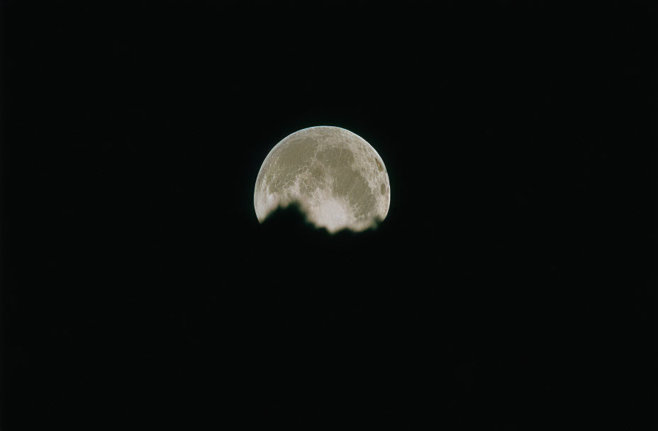 Waning gibbous moon partially obscured in dark night sky