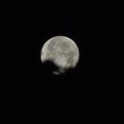 Waning gibbous moon partially obscured in dark night sky