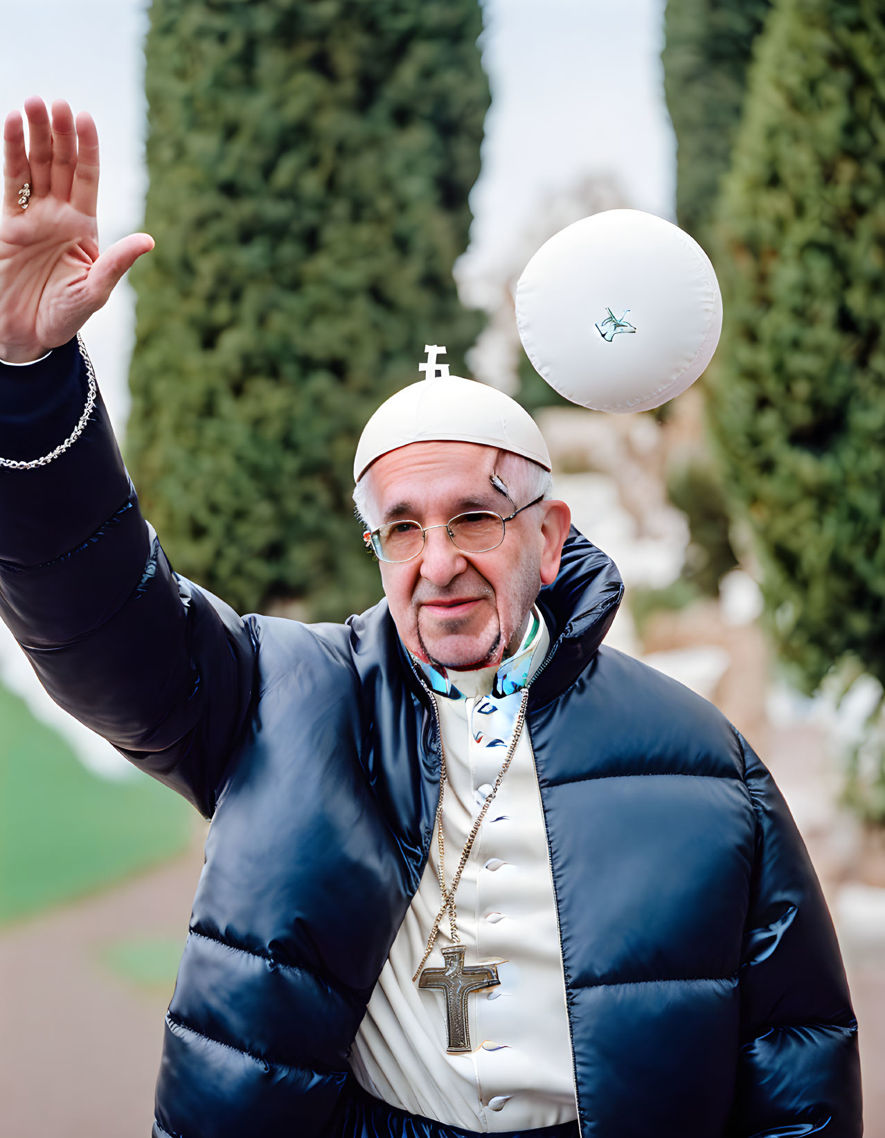 Person in Pope costume with glasses and cross, waving outdoors.