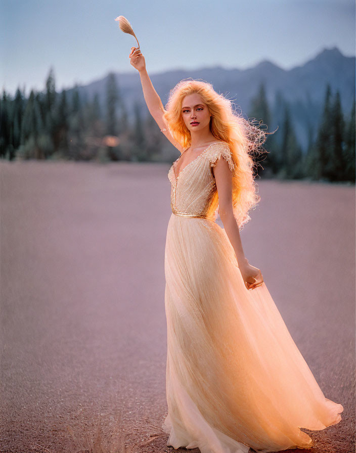 Woman in Beige Dress Holding Feather Against Mountain Backdrop