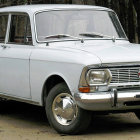 Vintage White Car with Distinctive Front Grille Parked by Rock Face