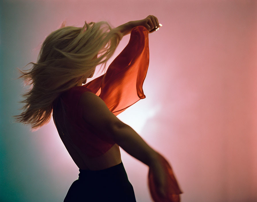 Blond woman twirling with red scarf on pink and teal background