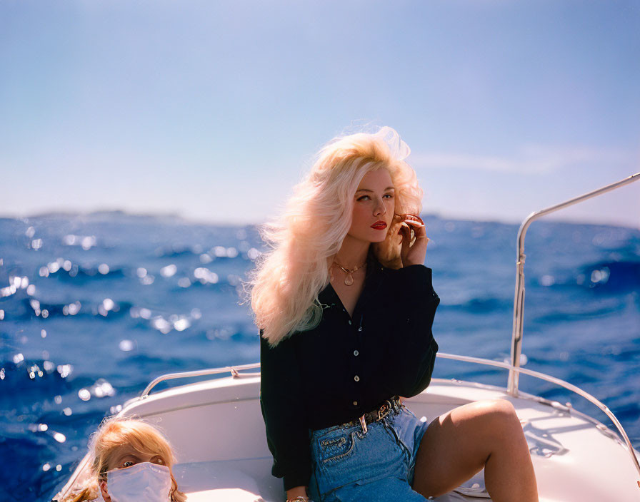 Blonde woman on boat with ocean background and another person.