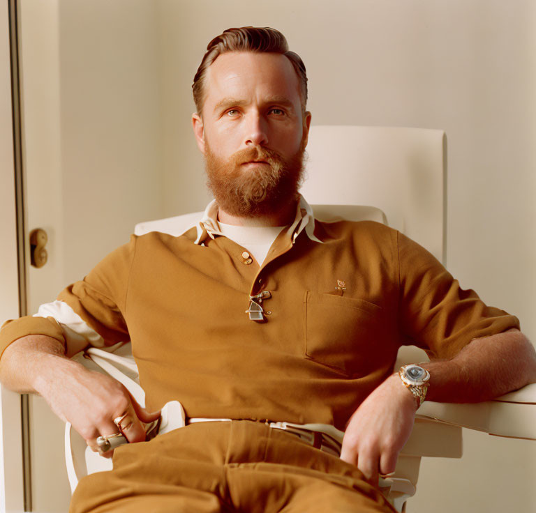 Bearded man in brown polo shirt sitting on chair