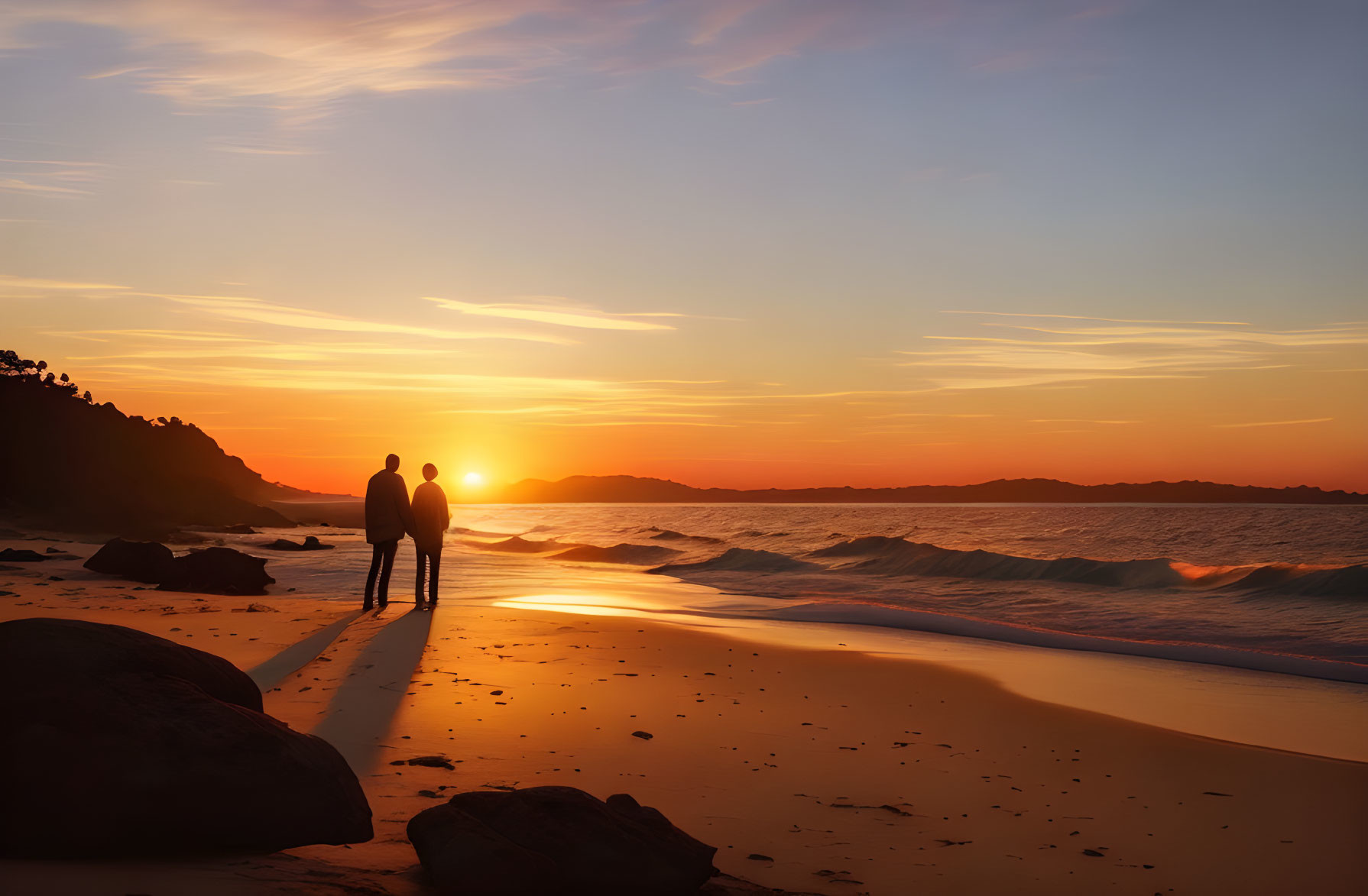 Couple walking on beach at sunset with waves and rocks in vibrant sky