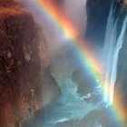 Majestic waterfall with vibrant rainbow and rugged cliffs