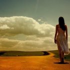 Woman Walking on Winding Path Through Golden Fields at Sunset