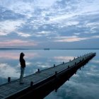 Tranquil digital art: Blue boathouse on pier with serene waters & sky