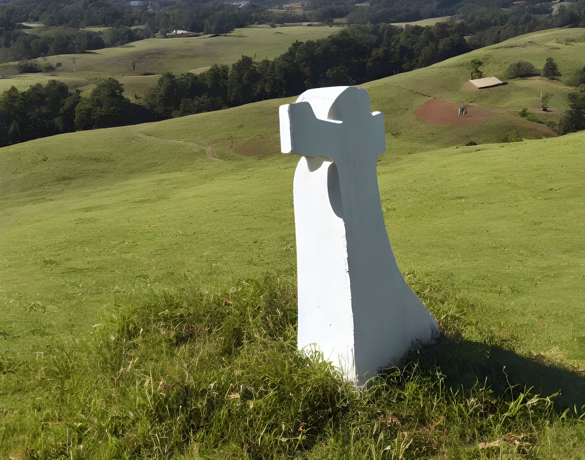 White Hammer Sculpture on Green Hillside with Trees and Fields