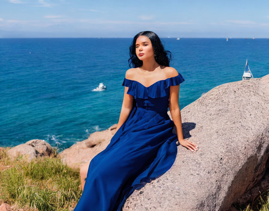 Woman in blue off-shoulder dress by ocean with boats, clear sky