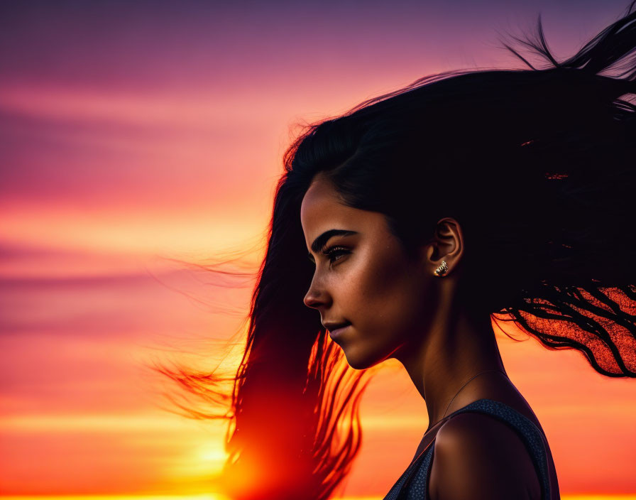 Woman's Silhouette with Flowing Hair in Vibrant Sunset Sky