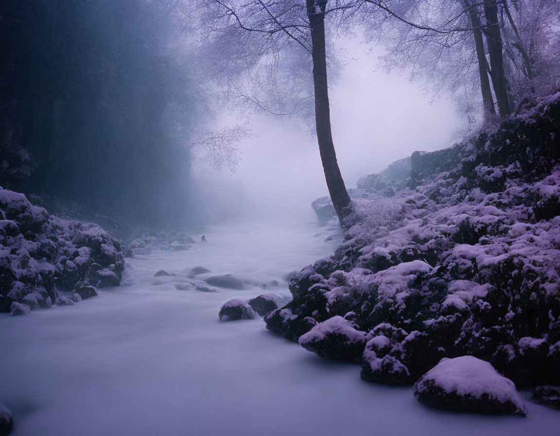 Snow-covered rocky creek in serene misty landscape
