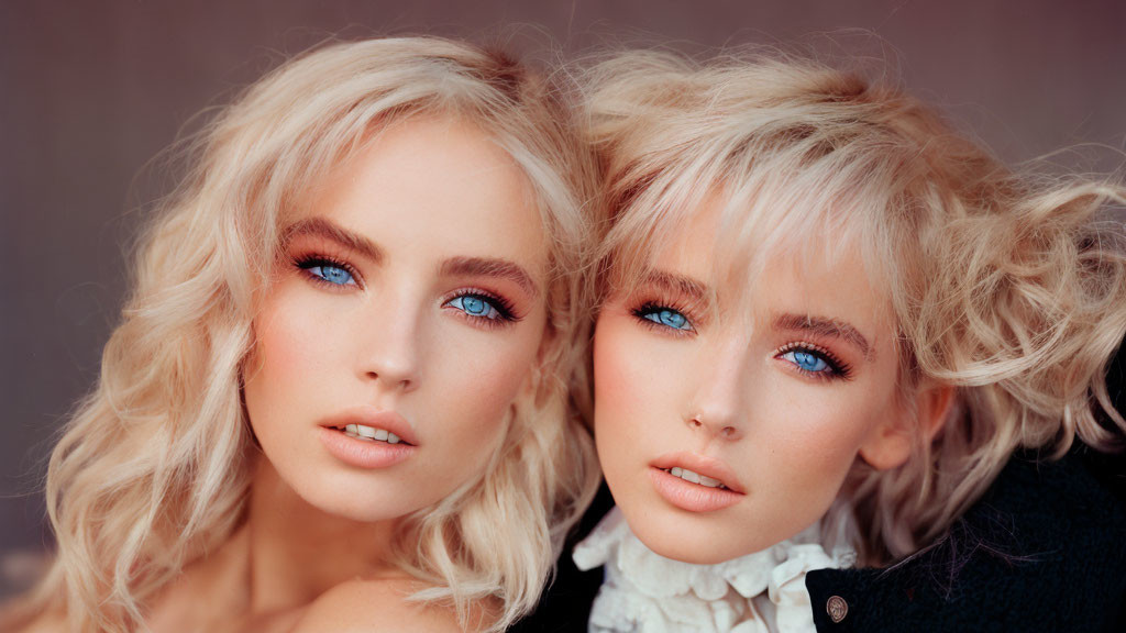 Twin individuals with blue eyes and blonde hair in close pose