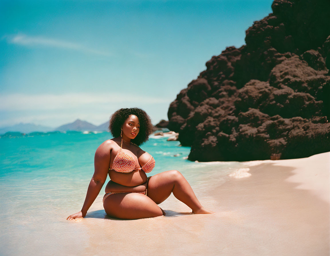 Woman posing confidently on sunny beach with blue waters and rocky formations