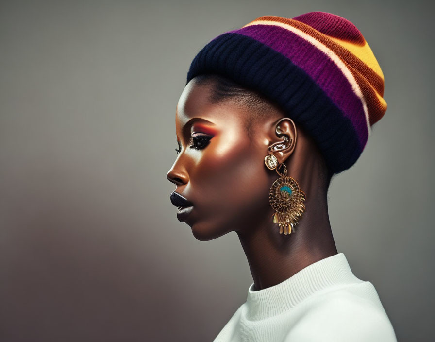 Person with Striking Makeup and Colorful Beanie in Ornate Earring