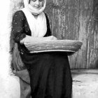 Monochromatic illustration of young girl in traditional attire with basket in snowfall