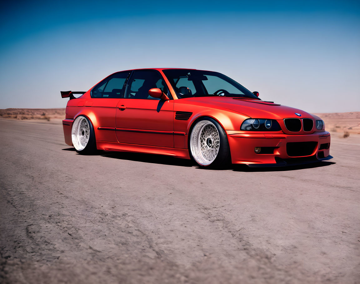 Vibrant orange BMW with sporty body kit and aftermarket wheels on desert road