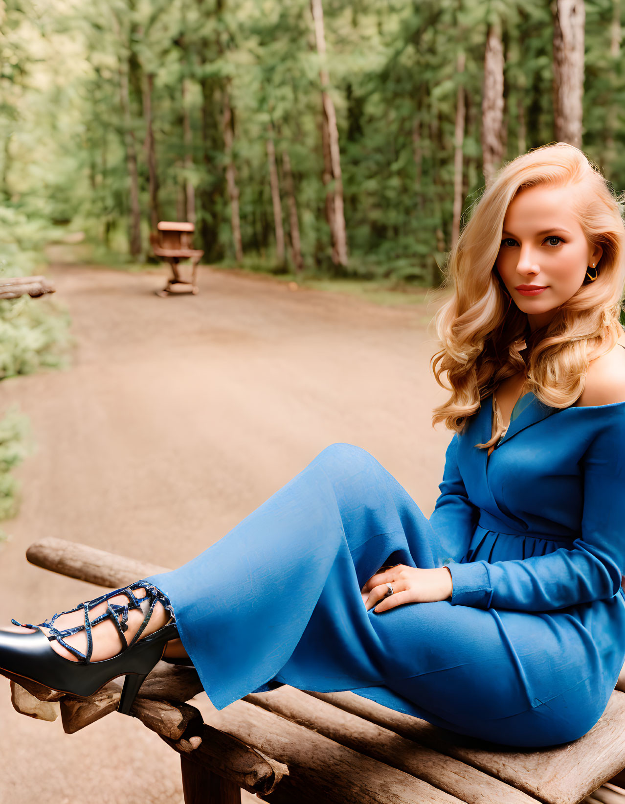 Woman in Blue Jumpsuit Sitting on Wooden Railing in Forest Trail