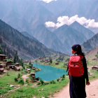 Woman with Red Backpack Overlooking Serene Mountain Village