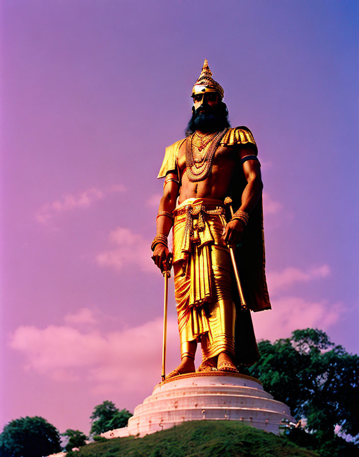 Golden male figure statue with staff and crown against blue sky