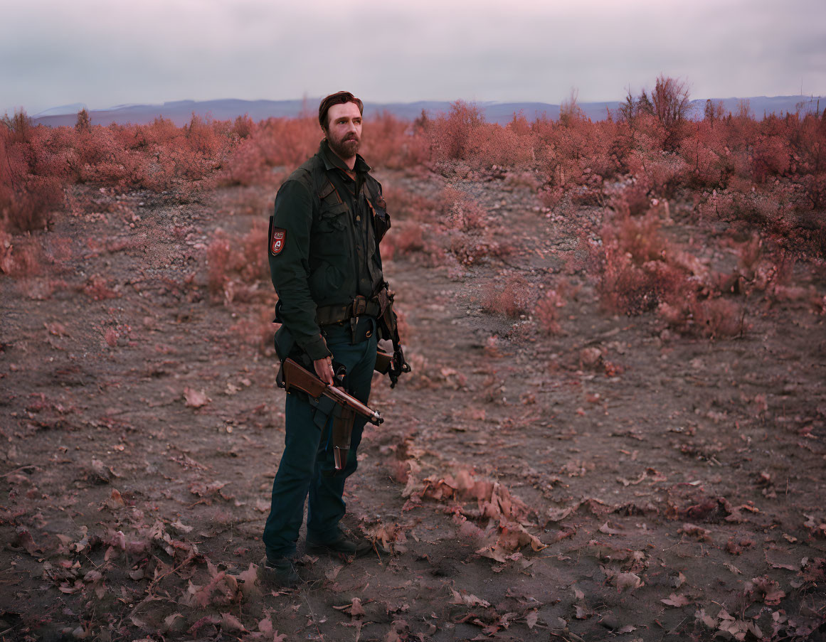 Military man in uniform with rifle in red landscape