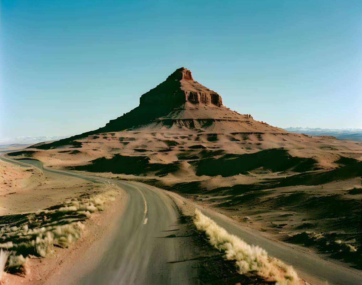 Desert landscape with road and mesa under clear sky