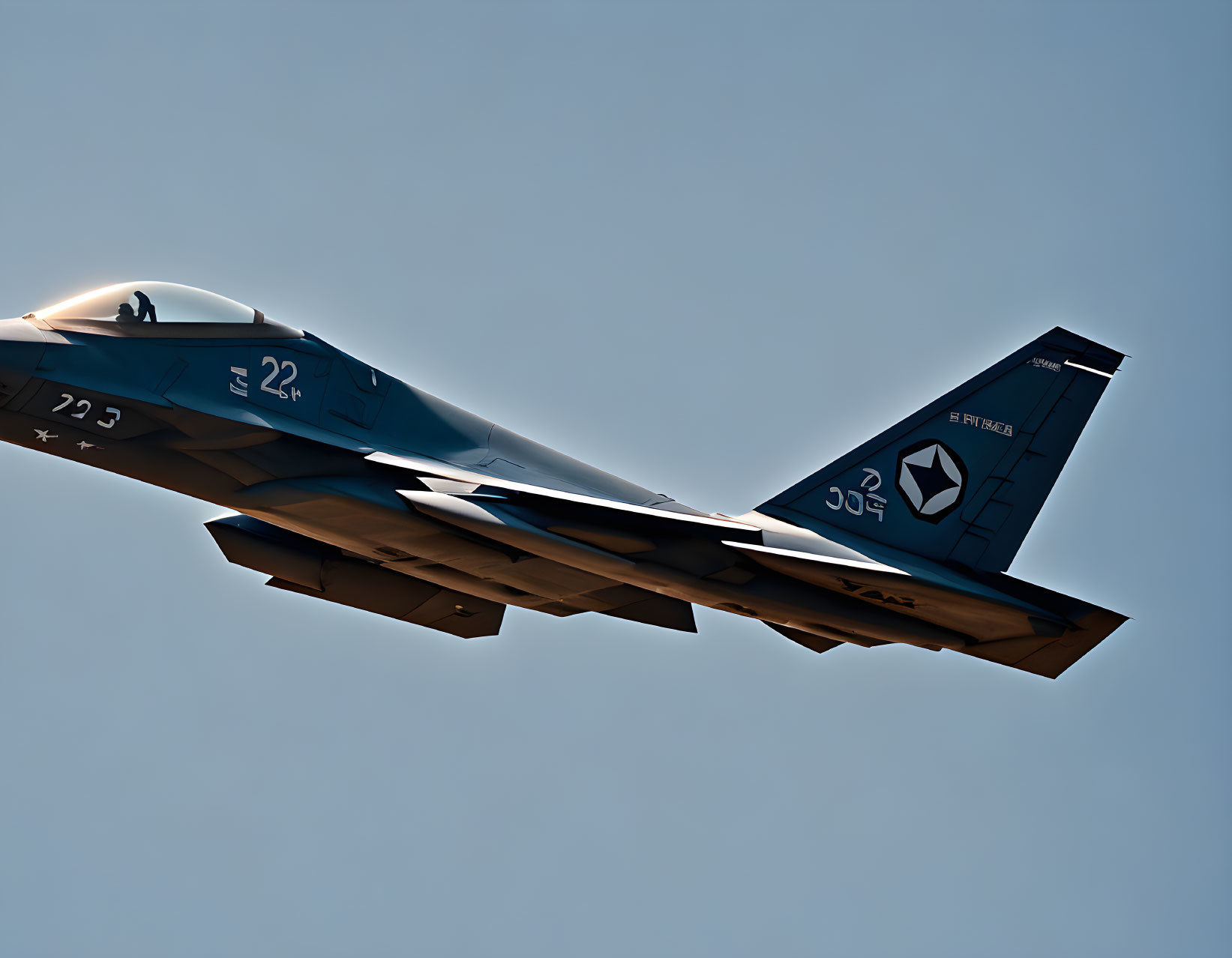 Blue fighter jet with tail number 22 and distinctive insignia soaring in clear blue sky