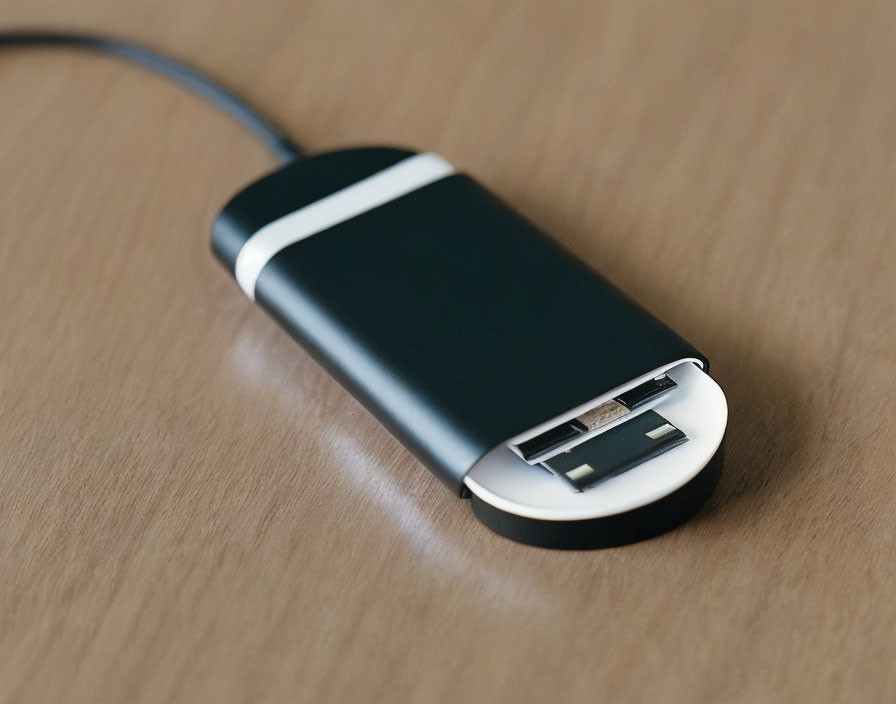 Black and Silver USB Flash Drive on Wooden Surface with Cable