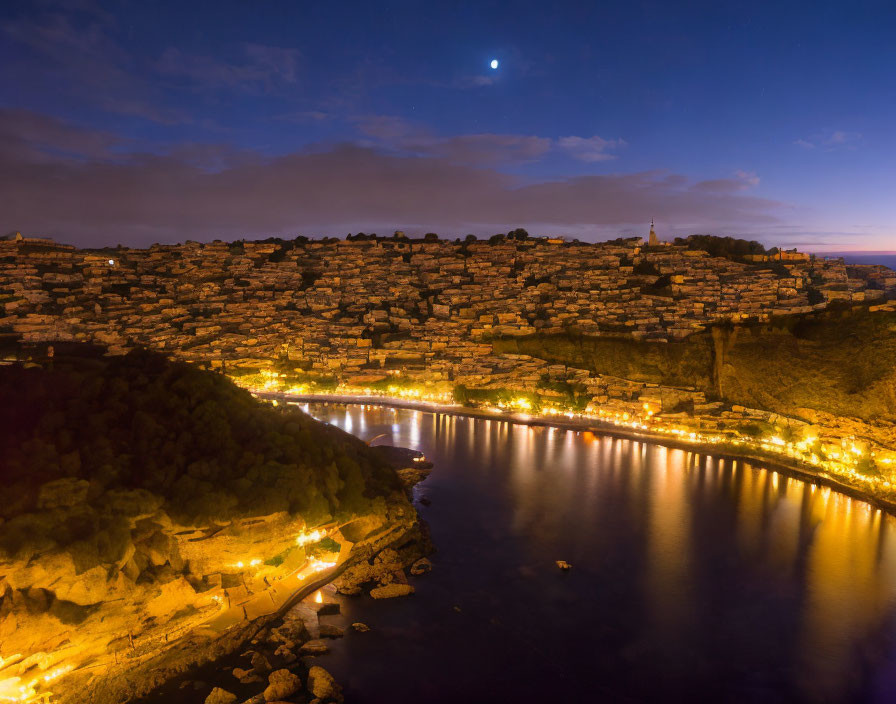 Coastal town at twilight with crescent moon and lit buildings