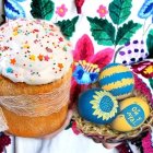 Illustration of doll with blonde curly hair in traditional dress and Easter eggs basket on floral background