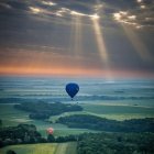 Hot Air Balloons Floating Over Lush Landscape at Sunset