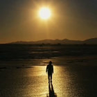 Person on Beach at Sunset with Waves and Large Moon