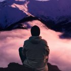 Individual on rock gazes at cloud sea, moon, mountains