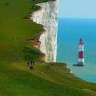 Scenic green hills, wildflowers, lighthouse, white cliffs, blue sea