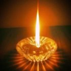 Tealight candle with bright flame on golden desert dunes backdrop