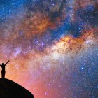 Person admiring vibrant, surreal sky from boat bow