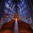 Church interior with rows of pews, altar, stained glass windows & soft multicolored light