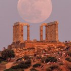 Surreal oversized moon over Greek village at dusk