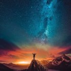 Person sitting on rock outcrop overlooking lava river under night sky