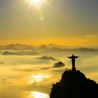 Iconic Christ the Redeemer statue at sunrise over coastal mountains and sea.