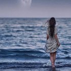 Woman in lace dress standing in ocean under overcast sky